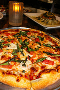 Freshly baked margherita pizza with basil. Photo by Brelyn Bashrum via Unsplash, used under the Unsplash License.