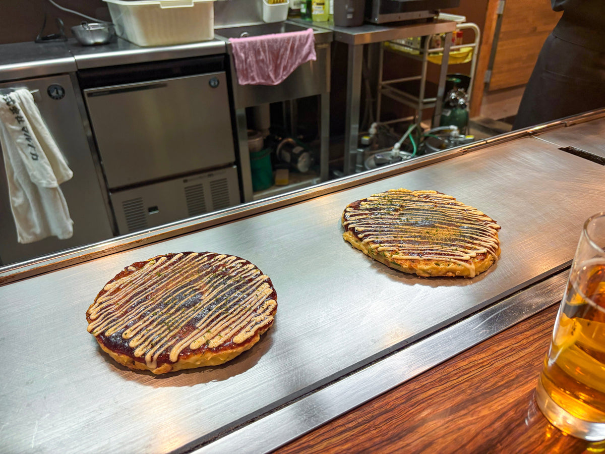 Fresh okonomiyaki topped with aonori and katsuobushi bonito flakes, a signature use for Spice Czar Bonito Flakes. Photo by Dale Cruse via Wikimedia Commons, CC BY 2.0.