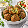 Serving illustration: crisp chickpea falafel with parsley, tahini and fresh vegetables. Prepared appearance varies.