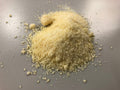 Close-up of finely grated Parmesan cheese showing the pale dairy-forward base of Spice Czar Garlic Parmesan Seasoning. Photo by Famartin via Wikimedia Commons, CC BY-SA 4.0.