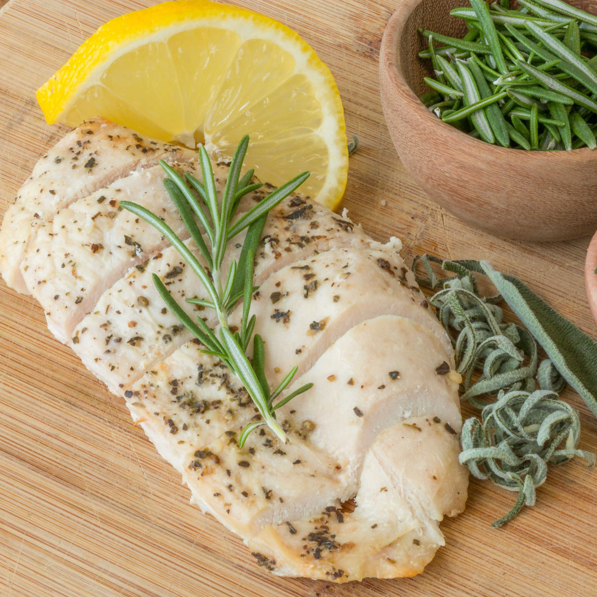 Serving suggestion for Poultry Seasoning: sliced chicken with visible dried herb flecks, rosemary, sage and lemon. Photo by Loren Castillo/Pexels; not a photograph of the dry blend or a verified cook using this product.