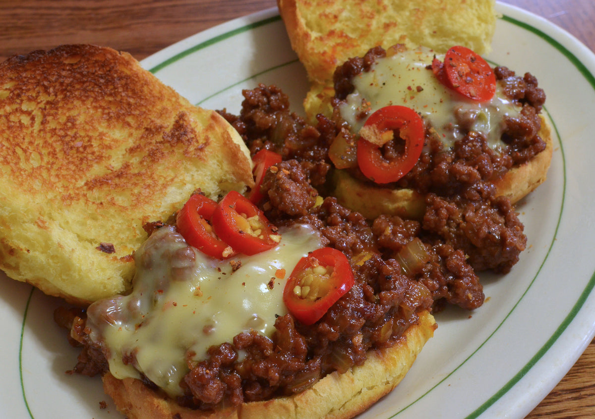 Serving suggestion: sloppy joe sandwiches on toasted buns with cheese and sliced peppers. Photo by jeffreyw, CC BY 2.0, via Wikimedia Commons; not a photograph of the dry seasoning.