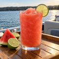 Serving suggestion: Watermelon Lime slushy with matching fruit beside a lake.